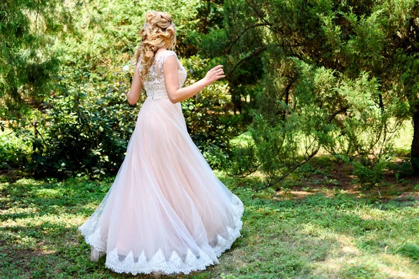 Beautiful bride in wedding dress spinning in the park. Dress develops in the wind. Happy bride in wedding dress turning