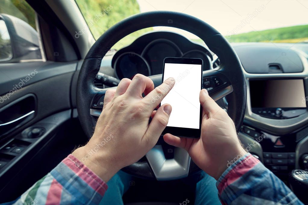 Close-up of man driver using smart phone in car. Driver sitting in car and holding mobile smart phone with isolated screen. Modern smartphone with white blank screen, copy space for text or design