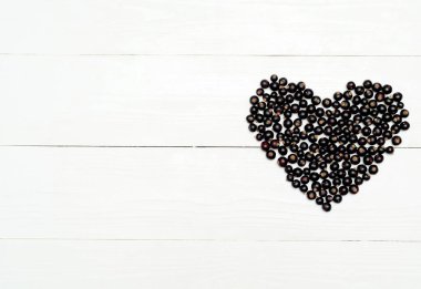 Siyah frenk üzümü kalp şekli, alanı kopyalayın. Sevgiliye arka plan. Beyaz ahşap masa üzerinde taze ahududu. Çilek kalp. Üstten görünüm, düz yatıyordu. Sevgililer günü tebrik kartı. Sevgi ve sağlıklı kavramı