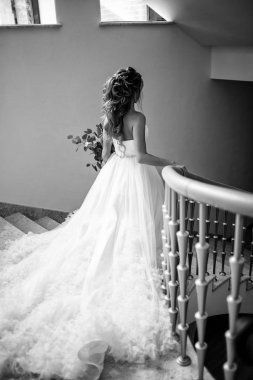 Tam uzunlukta vücut merdivenlerden arkadan görünüm yürüyüş eşarplı moda gelinlik giyen güzel gelin portresi. Siyah ve beyaz fotoğraf