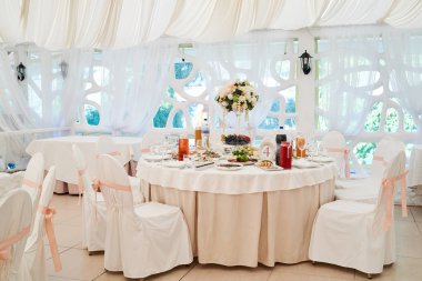 Düğün tablo ayarı ve sandalyeler Konuklar için. Restoran tablo yemek, çatal bıçak takımı ve tabak-çanak şenlikli olay için ayarla. Ikram Servisi. Düğün töreni. Masa aranjmanı 