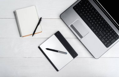 Açık dizüstü bilgisayar, boş boş defter ve beyaz tahta masada boş alan grafik tablet. Üstten görünüm, düz yatıyordu, kopya alanı metin için. İş kavramı