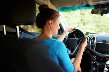 Arkadan görünüşü güzel genç kadın bir araba (veya ayakta trafik sıkışıklığı içinde) ve mobil akıllı telefon kullanarak, boş alan. Cep telefonu arabada oturan iş kadın