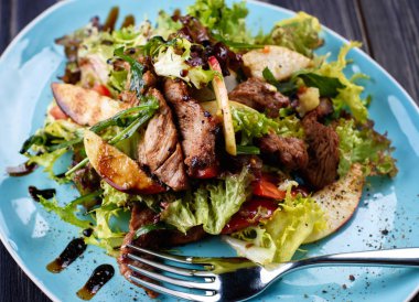 Dana salatası marul, elma, armut ve koyu ahşap arka plan, kopya alanı üzerinde mavi plaka üzerinde. Restoran gıda, yakın. Et salatası