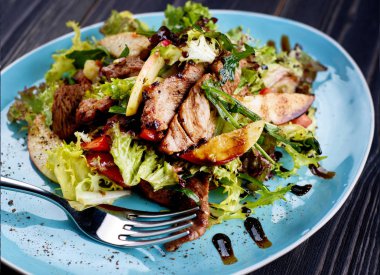 Dana salatası marul, elma, armut ve koyu ahşap arka plan, kopya alanı üzerinde mavi plaka üzerinde. Restoran gıda, yakın. Et salatası