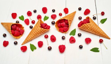 Olgun tatlı ahududu dondurma waffle koni, kopya alanı. Beyaz ahşap zemin, boş alan üzerine taze çilek. Yaz ve sağlıklı gıda kavramı. Üstten görünüm, düz yatıyordu. Çilek arka plan