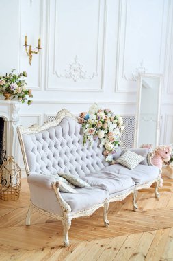 Yumuşak koltuk gri kumaş döşeme, yastıklar ve bu kopya alanı üzerinde çiçekler ile. Lüks zengin oturma odası iç tasarım zarif klasik mobilya, ayna ve şömine. Vintage Tekstil kanepe