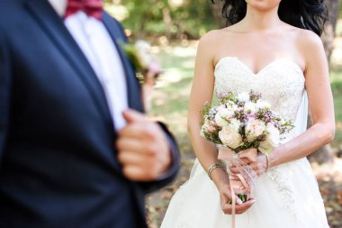Yemyeşil düğün buket gül ve yeşillik içinde damat ile holding beyaz elbiseli güzel gelin kopya alanı açık havada, bulanıklık. Gelinin elinde gelin buketi