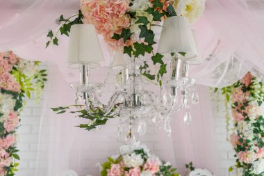 Yukarıda yatak yatak odasında asılı beyaz ve pembe çiçekli zarif kristal avize yakın çekim 