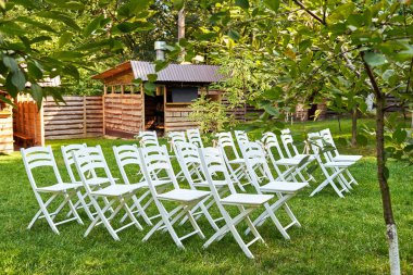 Kemer outroods, kopya alanı her tarafında taze çiçekler ile beyaz düğün sandalye. Konuklar bahçede düğün töreni için hazırlanan yeşil çim üzerinde için boş ahşap sandalye