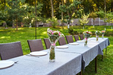 Düğün ya da Doğum günü tablo ayarını beyaz boş tabak, çatal bıçak takımı ve çiçeklerle gözlük ve yeşil çim açık havada, rattan sandalye kopyalama alanı. Resepsiyon düğün, Ziyafet 