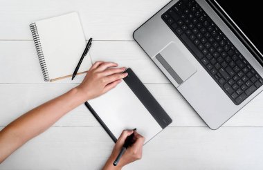 Üstten görünüm kadın el ile grafik tablet çizim ve rötuş görüntü dizüstü bilgisayarda kullanarak dijital tablet ve stylus kalem, boş alan. Dijital tablet üzerinde çalışan grafik tasarımcı. Boş defter