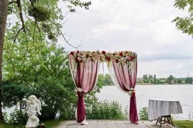Güzel düğün kemer kopya alanı bez ve nehir ya da göl açık havada, sahilde çiçeklerle dekore edilmiştir. Düğün Kur. Açık Hava düğün töreni için yer