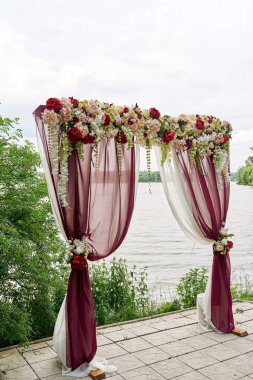 Güzel düğün kemer kopya alanı bez ve nehir ya da göl açık havada, sahilde çiçeklerle dekore edilmiştir. Düğün Kur. Açık Hava düğün töreni için yer