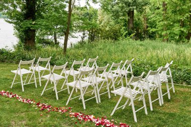 Kemer outroods, kopya alanı her tarafında taze gül yaprakları ile beyaz düğün sandalye. Konuklar bahçede düğün töreni için hazırlanan yeşil çim üzerinde için boş ahşap sandalye