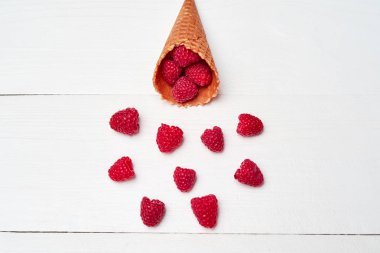 Olgun tatlı ahududu dondurma waffle koni, kopya alanı. Beyaz ahşap zemin, boş alan üzerine taze çilek. Yaz ve sağlıklı gıda kavramı. Üstten görünüm. Çilek arka plan