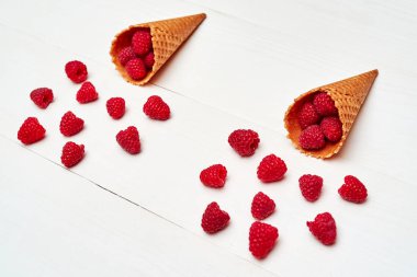 Olgun tatlı ahududu dondurma waffle koniler, kopya alanı içinde. Beyaz ahşap zemin, boş alan üzerine taze çilek. Yaz ve sağlıklı gıda kavramı. Çilek arka plan