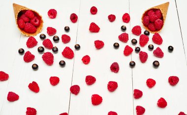 Üstten görünüm tatlı taze organik ahududu ve dondurma waffle koni siyah kuş üzümü. Taze çilek koni Beyaz ahşap zemin üzerinde. Yaz ve sağlıklı gıda kavramı. Çilek arka plan