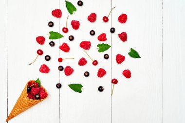 Üstten görünüm tatlı taze organik ahududu, siyah kuş üzümü ve kiraz gözleme koniler ile kopya alanı içinde. Taze çilek koni Beyaz ahşap zemin üzerinde. Yaz ve sağlıklı gıda kavramı 