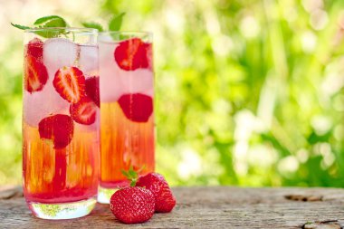 Çilek limonata, buz ve nane ile yeşil arka plan açık havada, bardaklarda kokteyl alanı kopyalayın. Canlandırıcı yaz berry içeceği. Köpüklü içecek gözlük 