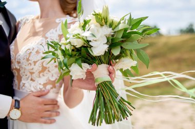 Güzel gelin buketi beyaz taze çiçek ve yeşillik şeritler gelinin elinde, seçici odak. Gelin düğün buket onu, sarılma damat süre tutarak kopyalama alanı