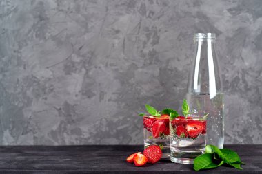 Maden suyu, çilek ve naneli limonata bardak bardak su içinde şişeyle ahşap masa, kopya alanı bırakır. Canlandırıcı yaz berry içeceği. Köpüklü su içki çilek dilimleri ile