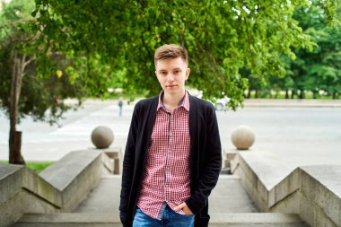 Ekose gömlek ve şehir, kopya alanı merdivenlerde yürürken kot rahat genç adam portresi. Seyahat ve Turizm kavramı. Taş merdivenle açık havada duran öğrenci