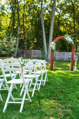 Kemer outroods, kopya alanı her tarafında taze çiçekler ile beyaz düğün sandalye. Konuklar bahçede düğün töreni için hazırlanan yeşil çimenlerin üzerinde için boş ahşap sandalye