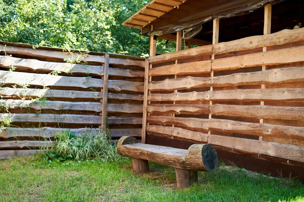 Wooden rough bench against wood plank wall outdoor, copy space. Empty wooden bench made of logs. Lonely place