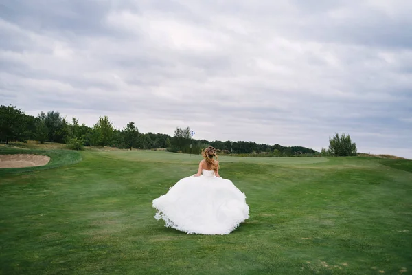 Tam uzunlukta vücut moda beyaz gelinlikle yeşil golf sahası ile geri görünüm kaçmak eşarplı güzel gelin portresi. Kaçak gelin, kopya alanı