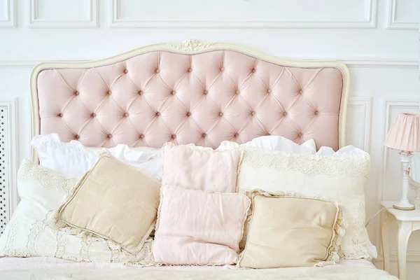 Büyük düğmeli yatak başlığı, bej ve pembe yastıklar, fotokopi alanı. Pembe ve beyaz renkli kadın yatak odası. Chesterfield stili damalı yumuşak yatak başlığı, elmas desenli