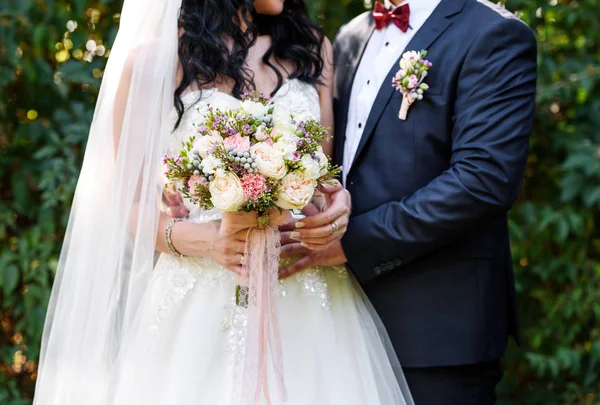 Dantel şeritler gelinin elinde güzel yemyeşil gelin buketi. Mutlu gelin ve damat düğün töreni sonrası, boş alan sarılma. Düğün çifti, yeni evliler, boş alan