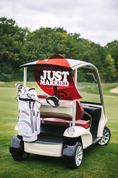 Just married sign on red heart on empty golf car outdoors. Wedding concept. Golf cart on golf course, copy space. Golf club