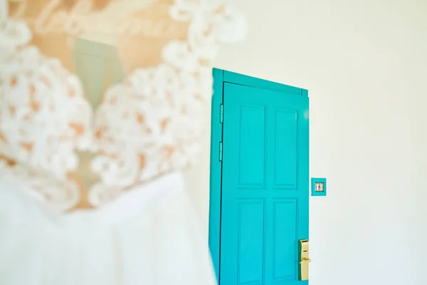 Blue wooden door with number eight and wedding dress for bride in blur hanging on hanger with inscription in Russian \'\'Bride\'\'. Bride morning, copy space