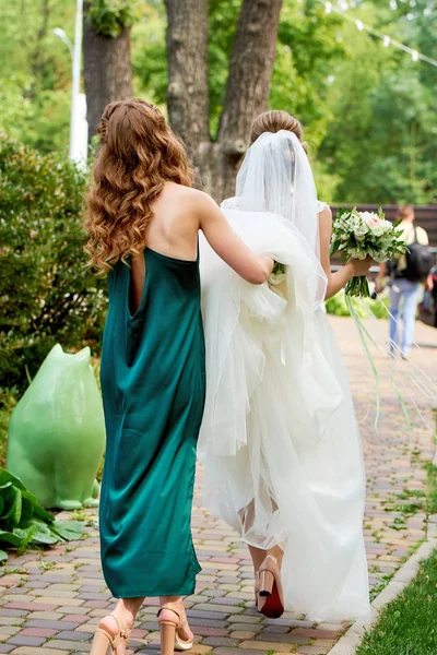 Dama Honra Vestido Esmeralda Segurando Vestido Noiva Trem Enquanto Caminham — Fotografia de Stock