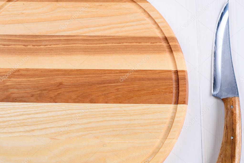 Empty circular wooden cutting board for bread, pizza or steak serve and knife on white kitchen table background, copy space. Top view, flat lay