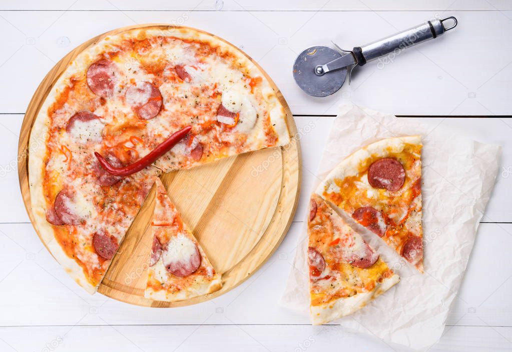 Hot sliced classic pepperoni pizza on wooden board, close up. Fresh pizza with pepperoni, mozzarella and tomato sauce, copy space. Italian traditional cuisine, food