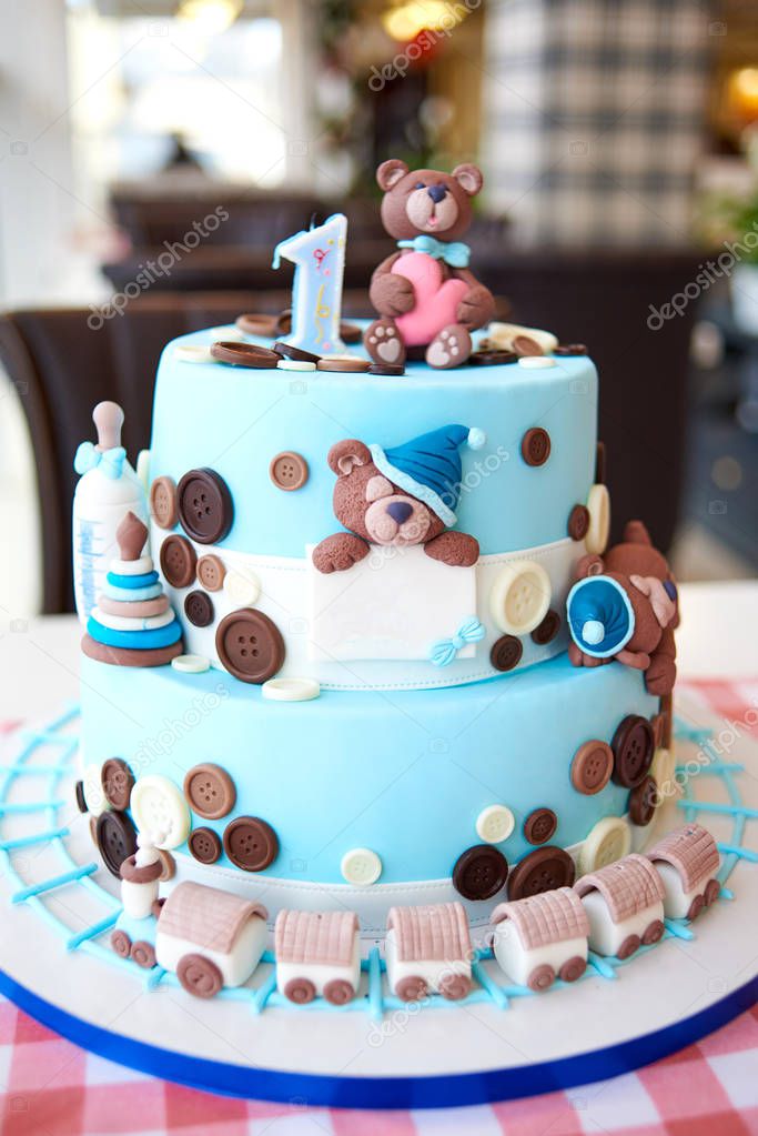Round multi tiered blue  birthday cake decorated with button, toys, bears, locomotive and number one on the top, copy space for text 