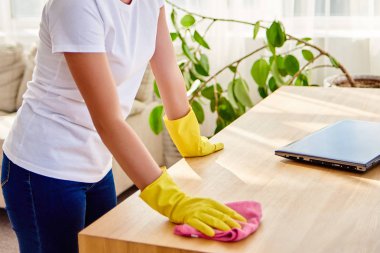 Beyaz gömlek ve evde temizlik ve toz pembe bez ile ahşap tablel silerek sarı koruyucu lastik eldiven kadın resim kırpılmış, uzay kopyalayın. Ev işleri, cleanig ve ev işleri kavramı