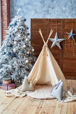 Hediyeler ve Kızılderili çadırı, çocuk odası, kopya alanı ile Noel ağacı. Noel süsleri. Çıkarmaya odası iç ile dekore edilmiş oyun tipi çadır. İskandinav tarzı 