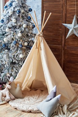 Hediyeler ve Kızılderili çadırı, çocuk odası, kopya alanı ile Noel ağacı. Noel süsleri. Çıkarmaya odası iç ile dekore edilmiş oyun tipi çadır. İskandinav tarzı 