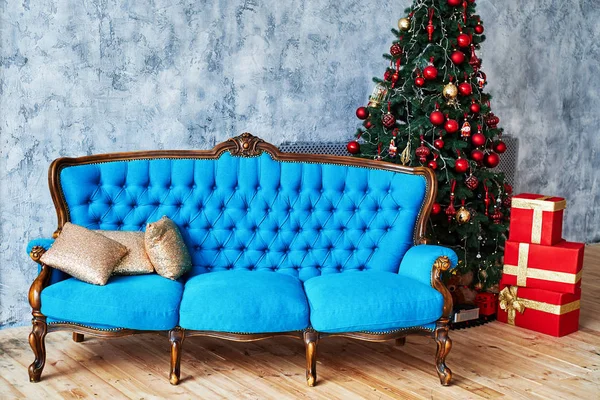 Christmas morning, copy space. Classic apartments with blue buttoned sofa, decorated fir tree and red gift boxes. Christmas interior