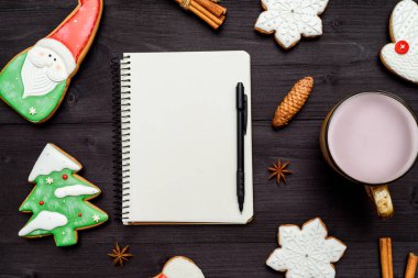 Açık boş defter, ev yapımı gingerbread çerezleri ve koyu ahşap masa üzerinde kakao fincan. Üstten görünüm, düz yatıyordu. Noel arka plan. Yeni yıl kararları, gol, boş alan