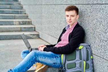 Öğrenci açık havada Üniversitesi Kampüs merdivenlerde oturan ve laptop ile çalışma, sınavlara hazırlık, yazarak, internet'te sörf, dinlenme, kopya alanı sırt çantası ile. Teknoloji, eğitim kavramı