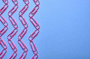 Pastel pembe kağıt kliplerinde mavi arka plan, kopya alanı. Üstten görünüm, düz yatıyordu. Okul, Kolej, eğitim kavramı hazırlıkları. Dalga ataç yaptı. Arka plan