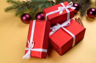 Noel arka plan kırmızı hediye kutuları, köknar ağacı dalları ile cam topları, çam kozalakları ve tarçın altın arka plan üzerinde boş alan. Kırmızı lüks yeni yıl hediye, kopya alanı
