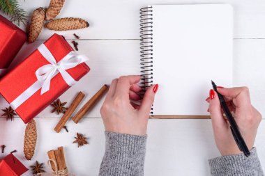 Üstten görünüm Noel arka plan boş boş günlüğü ile ve kızın elleri kalem Beyaz ahşap zemin üzerinde boş alan gol yazma ile. Düz yatıyordu, en iyi görünümü