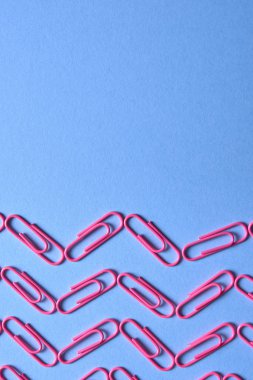 Pastel pembe kağıt kliplerinde mavi arka plan, kopya alanı. Üstten görünüm, düz yatıyordu. Okul, Kolej, eğitim kavramı hazırlıkları. Dalga ataç yaptı. Arka plan