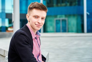 Oturma ve geri kalan üniversite kampüsünde açık havada, kopya alanı olan gülümseyen erkek öğrenci portresi. Eğitim, dinlenmek ve rahatlamak, seyahat ve Turizm kavramı 