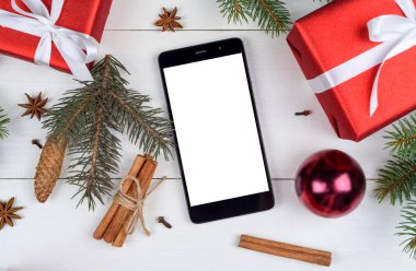 Noel süsleri, kopya alanı ile app sunum için boş beyaz ekran ile mobil akıllı telefon yakın çekim. Noel hediyeleri, köknar ahşap arka plan üzerinde dalları. Düz yatıyordu, en iyi görünümü